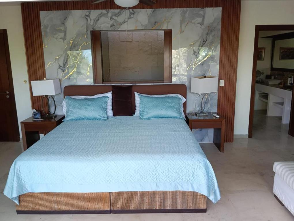 a bedroom with a large bed with blue pillows at Lovely modern beach Villa in Cruz de Huanacaxtle