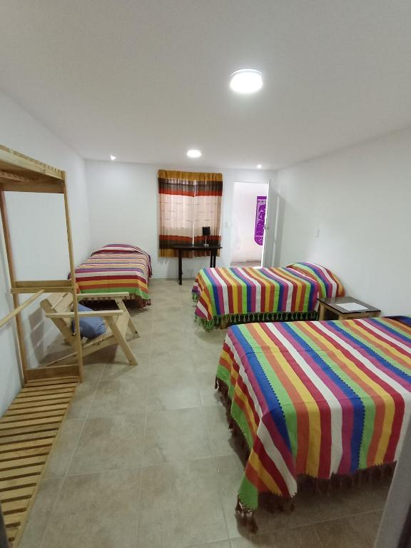 a room with three beds and a piano at Iguana Coliving in Oaxaca City