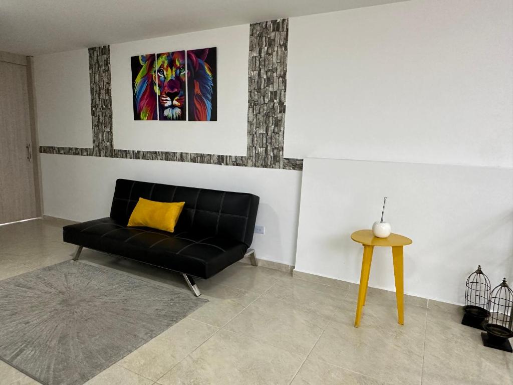 ein Wohnzimmer mit einem schwarzen Sofa und einem gelben Kissen in der Unterkunft El refugio in Pereira