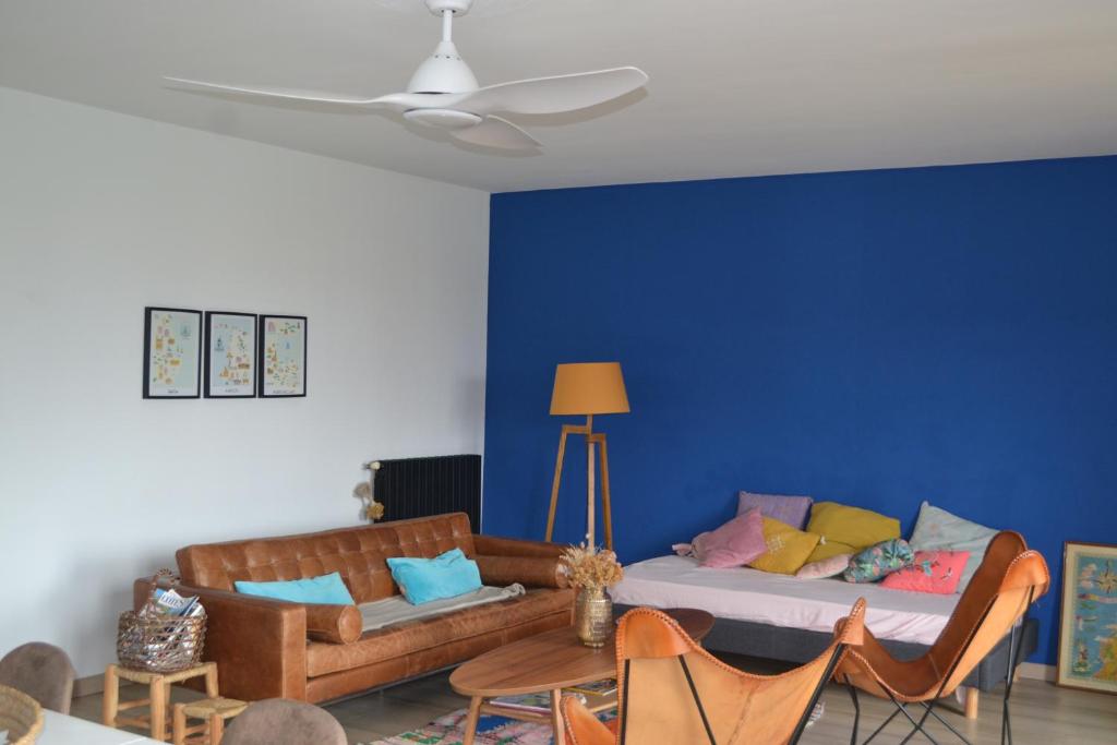 un salon avec un canapé et un mur bleu dans l'établissement Appart 175m2 idéalement situé Stationnement gratuit bas villa, à Ajaccio
