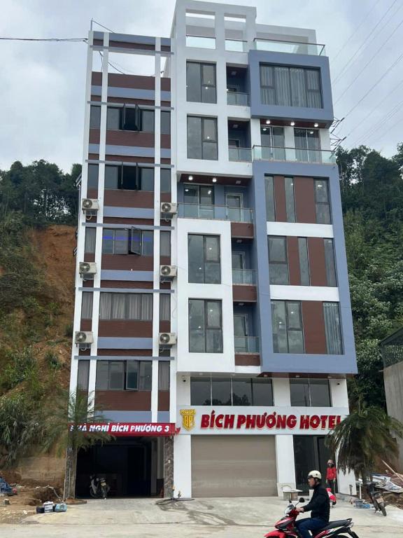 a man riding a motorcycle in front of a building at Bich Phuong Hotel 3 in Ha Giang