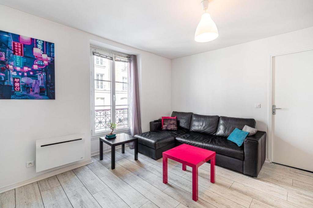 - un salon avec un canapé en cuir noir et un tabouret rouge dans l'établissement GuestReady - Charming Canal St-Martin Retreat, à Paris