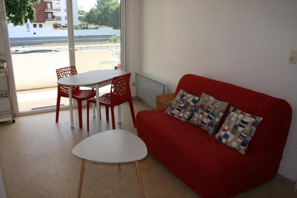 a living room with a red couch and a table at Appt 2 pièces LA ROCHELLE - LR030-E16 in La Rochelle