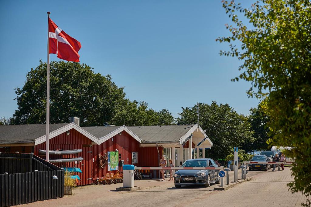 a red building with a flag on top of it at Husodde Strand Camping & Cottages in Horsens