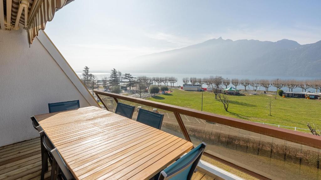 d'une table et de chaises en bois sur un balcon avec vue. dans l'établissement Les Cygnes - exceptional location with lake view - 3 bedrooms, à Aix-les-Bains