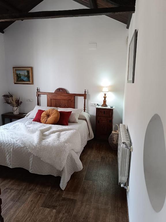 a bedroom with a bed with white sheets and red pillows at Casa Rural Gafas in El Toboso
