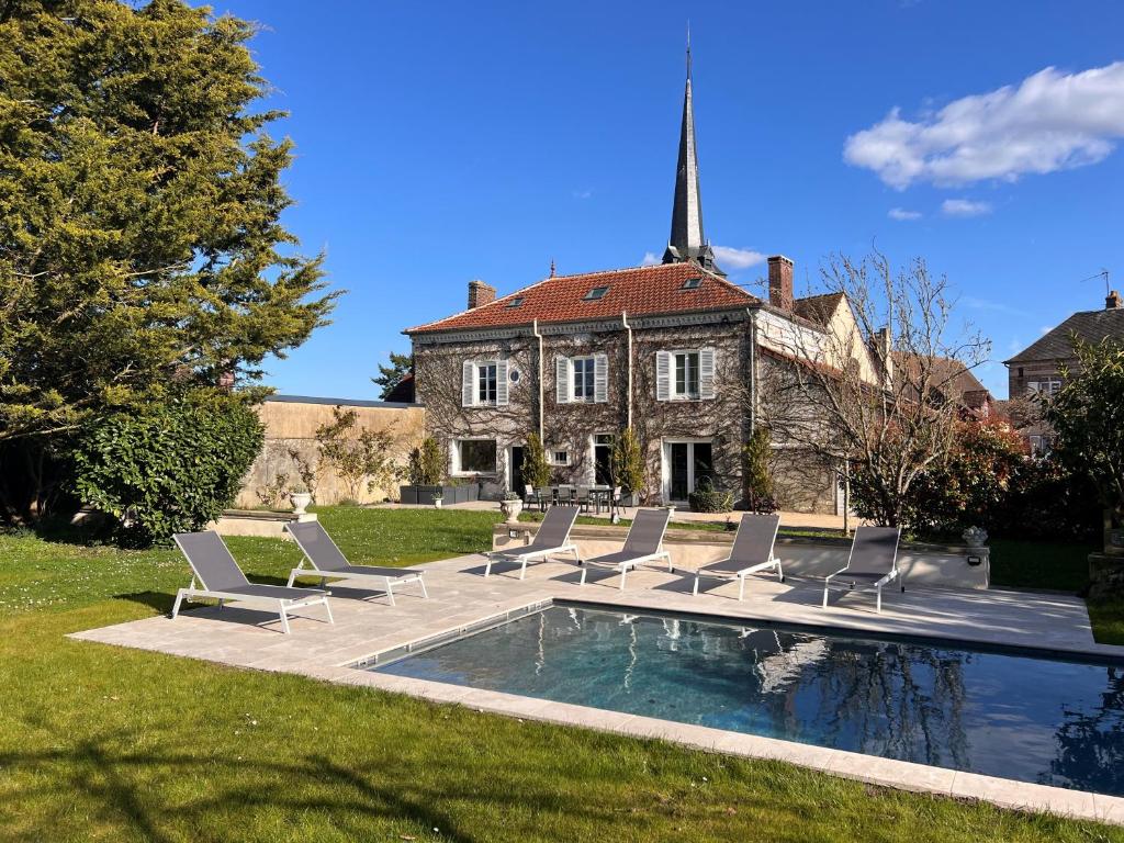 une maison avec des chaises et une piscine en face de celle-ci dans l'établissement Bel Air, à Bois-le-Roi