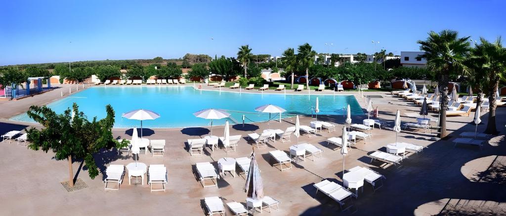 een uitzicht over een zwembad met stoelen en parasols bij Villa Mery Villaggio Chiusurelle in Torre Lapillo