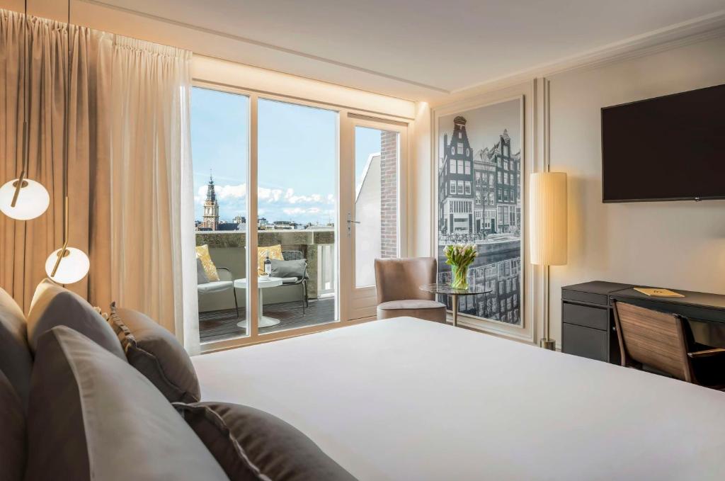 a hotel room with a bed and a large window at Anantara Grand Hotel Krasnapolsky Amsterdam in Amsterdam