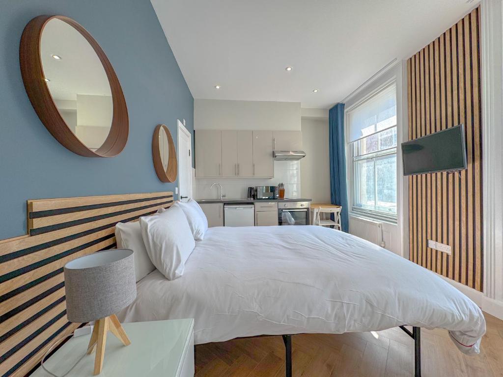 a bedroom with a large white bed and a mirror at Earls Court Residences in London