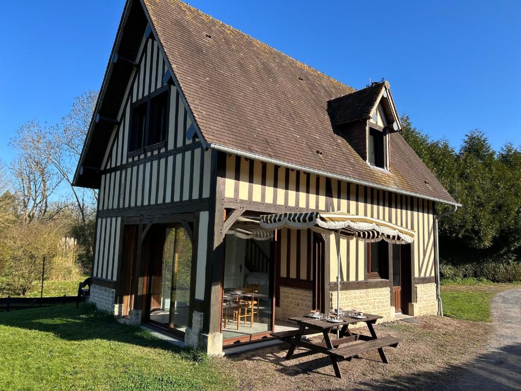 - un bâtiment avec une table de pique-nique devant dans l'établissement Le Cottage aux portes de Deauville, à Bonneville-sur-Touques