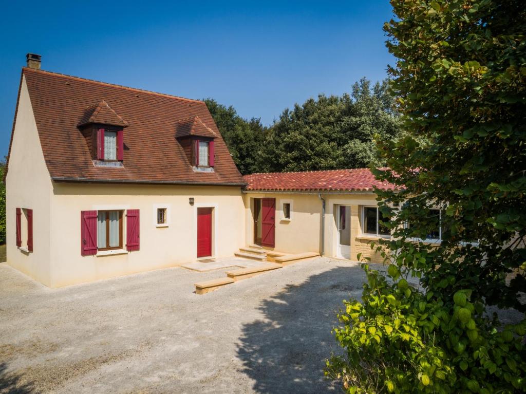 une maison avec des portes rouges et une cour dans l'établissement Gîte de Caillou, à Berbiguières