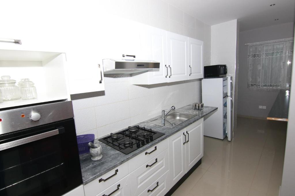 cocina con armarios blancos y fogones negros en Villa Racine, en Porto Novo