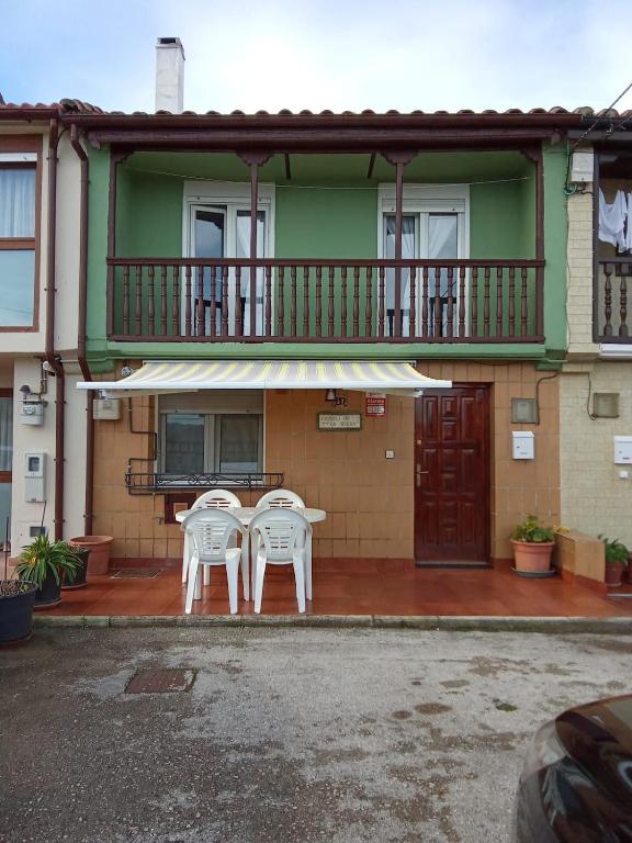 two chairs and a table in front of a house at La casa del Rubio in Pedreña
