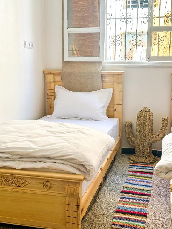 a bedroom with a wooden bed with a cactus next to a window at Surf and Stay Anza - Surf Territory in Agadir