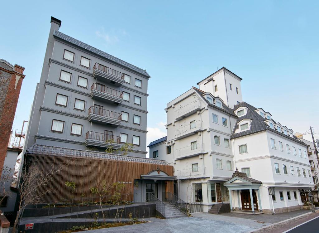 dois edifícios altos ao lado um do outro numa rua em Matsumoto Hotel Kagetsu em Matsumoto