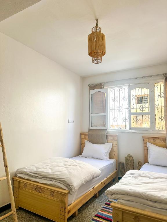 two beds in a room with two windows at Surf and Stay Anza - Surf Territory in Agadir