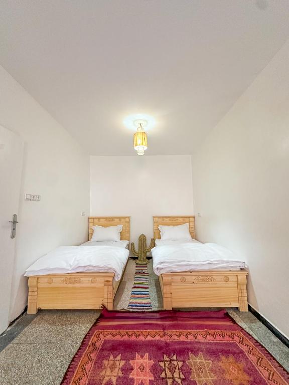 two twin beds in a room with a rug at Surf and Stay Anza - Surf Territory in Agadir