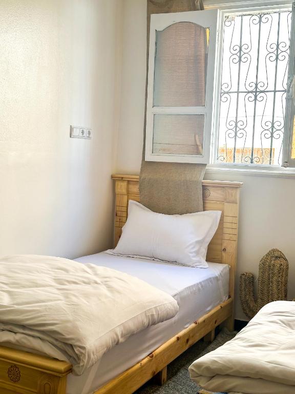 two beds in a room with a window at Surf and Stay Anza - Surf Territory in Agadir