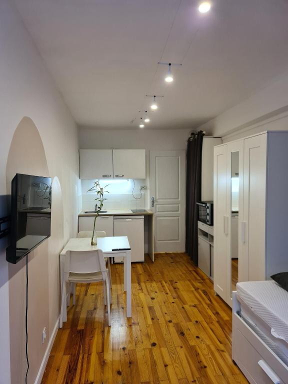 - une cuisine avec une table et une table et des chaises blanches dans l'établissement Studio cosy avec clim et jardin, à Fontaine