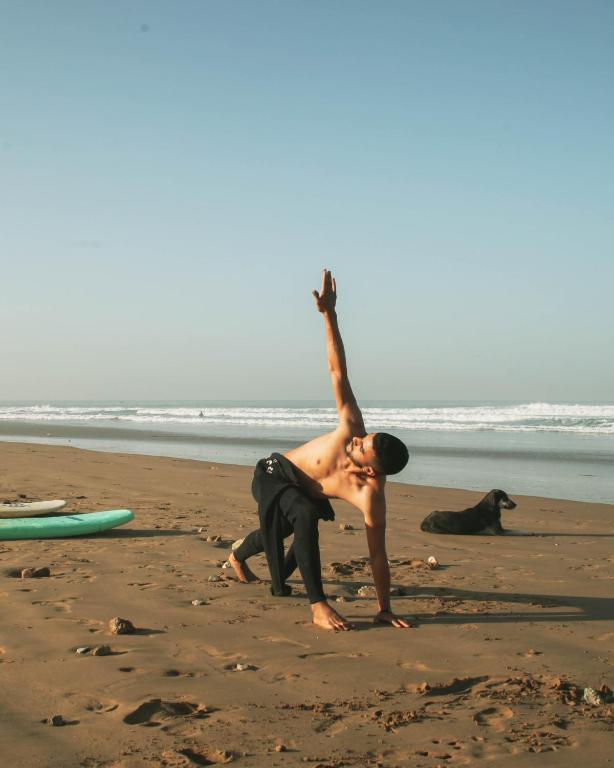 a man standing on a beach with his arm in the air at Surf and Stay Anza - Surf Territory in Agadir