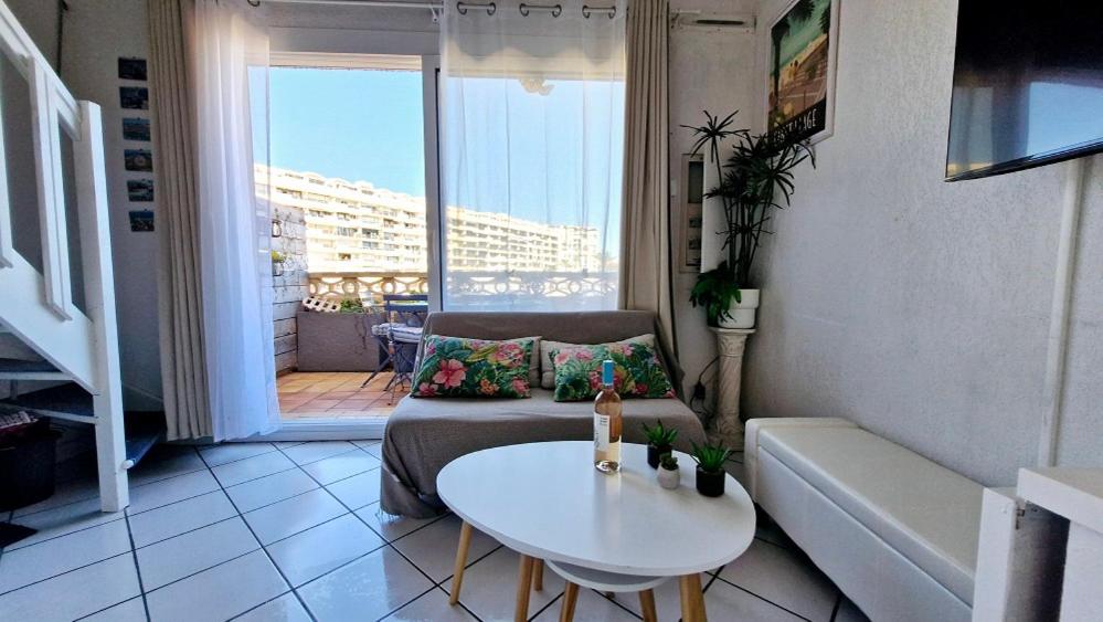 un salon avec un canapé et une table dans l'établissement Le Chrystina - T2 au port avec terrasse vue mer - Parking WIFI clim, à Saint Cyprien Plage