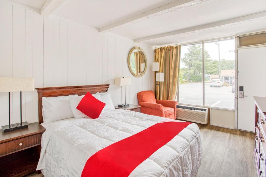Una habitación de hotel con una cama roja y blanca y una ventana. en OYO Inn Kernersville, en Kernersville