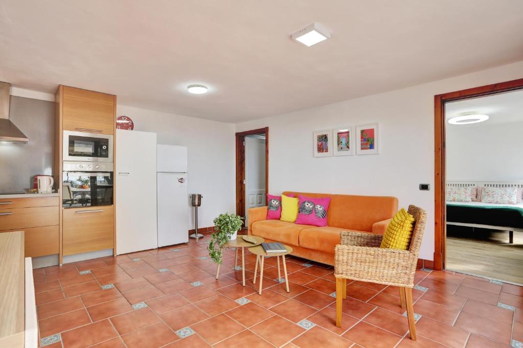 salon z pomarańczową kanapą i kuchnią w obiekcie Apartment Private Heated Pool w mieście El Draguito