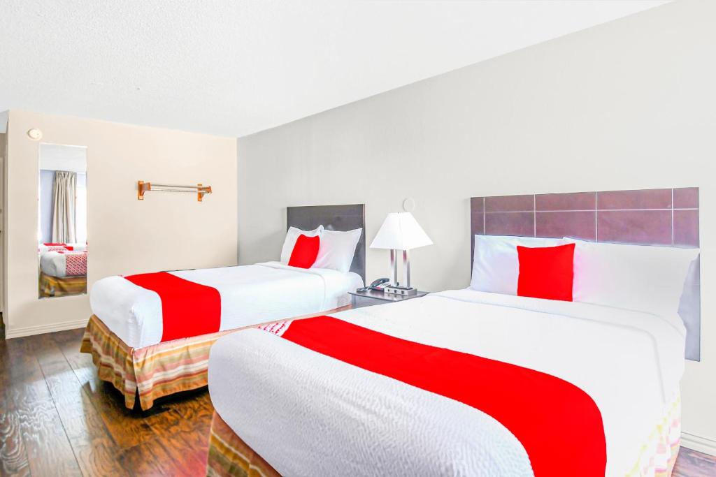 two beds in a hotel room with red and white sheets at Americas Best Value Inn Irving DFW Airport South in Irving