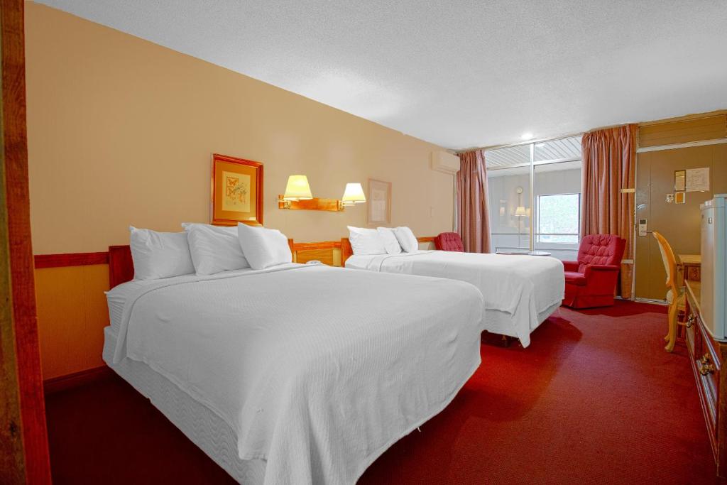 Una habitación de hotel con dos camas con sábanas blancas. en HomeTown Inn By OYO - Liberal, KS, en Liberal