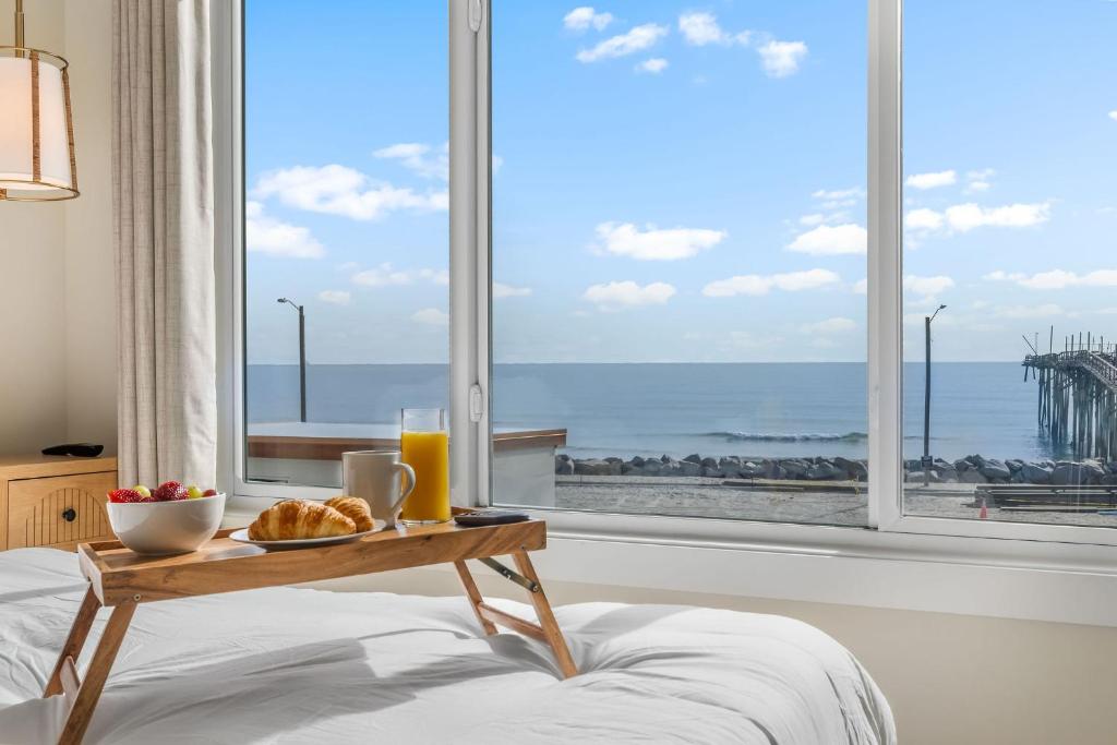 カロライナビーチにあるOcean Breeze Oasis Oceanfront Condo Pool & Elevatorのベッド1台(クロワッサンのトレイ、朝食付きテーブル付)