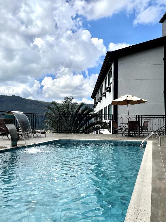 a swimming pool with a fountain in front of a building at Serra Palace Hotel in Ouro Branco