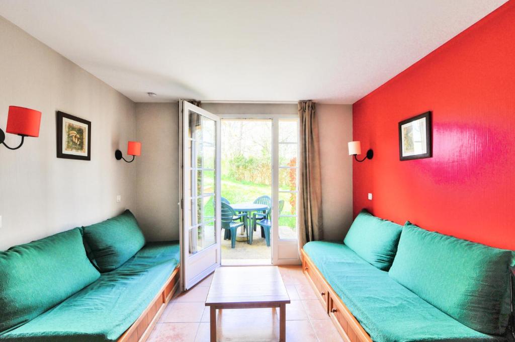 - un salon avec un canapé vert et des murs rouges dans l'établissement La résidence du Lac - maeva Home - Appartement 2 pièces 5 personnes - Sélection MAE-7651, à Monflanquin