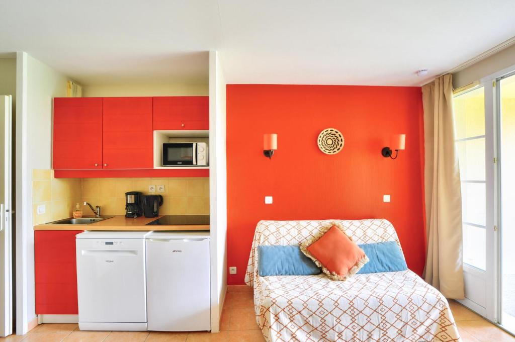 - une cuisine avec des placards rouges et une chaise dans la chambre dans l'établissement La résidence du Lac - maeva Home - Appartement 2 pièces 4 personnes - Sélection MAE-5911, à Monflanquin