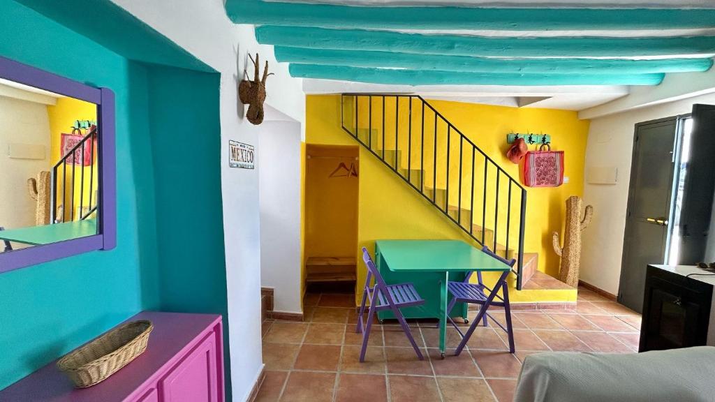 a room with a table and chairs and a staircase at La Casa de los Colores in Olvera
