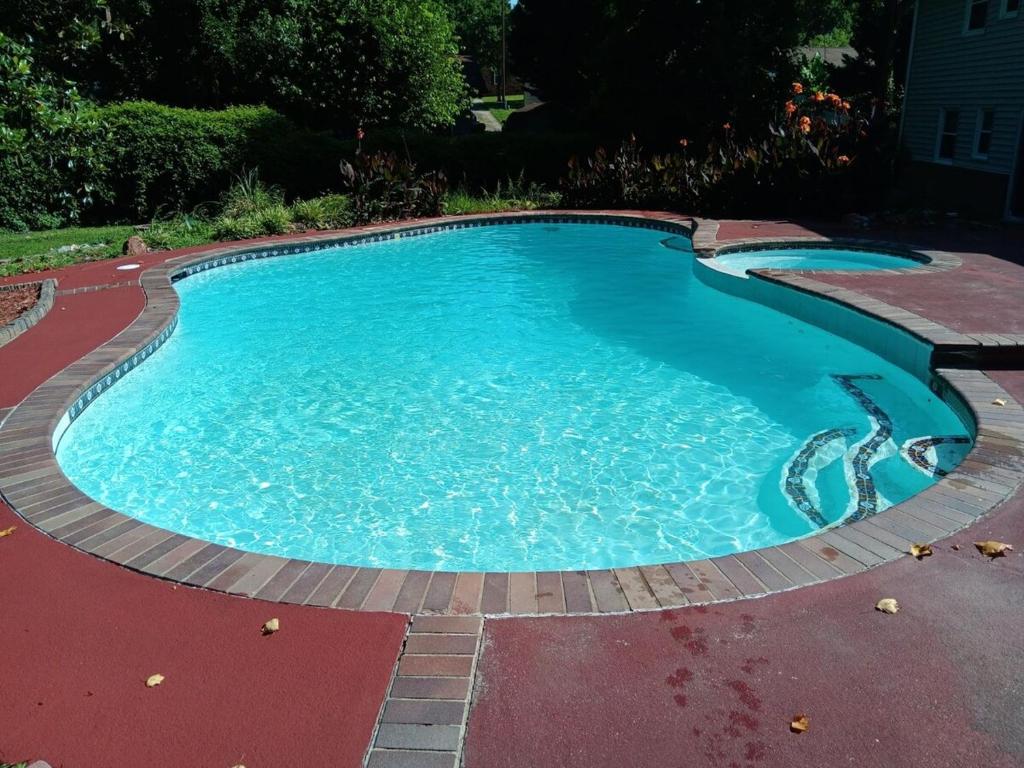 a large swimming pool with blue water in a yard at Theater, heated pool and hot tub near HPU and Furniture Market in Jamestown