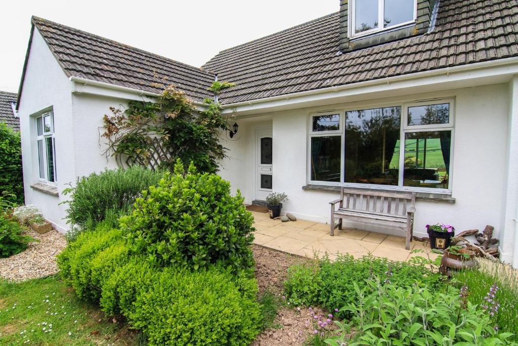 a white house with a bench in the front yard at Jamie's Georgeham in Croyde