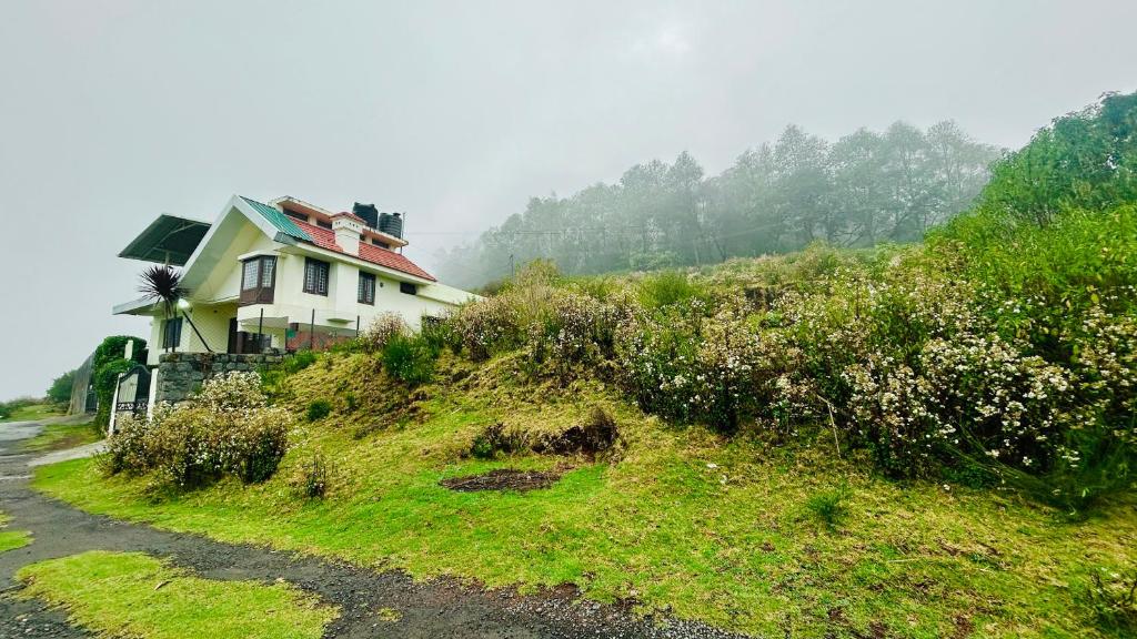a house on the side of a grassy hill at Away From Home - 1 - Rooms In Ooty, Home Stay Ooty in Ooty