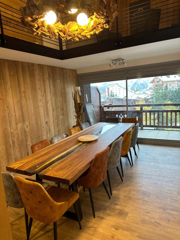 ein großer Holztisch in einem Raum mit Stühlen in der Unterkunft Spacieux et beau duplex au pied des pistes et centre station avec balcon in Les Deux Alpes
