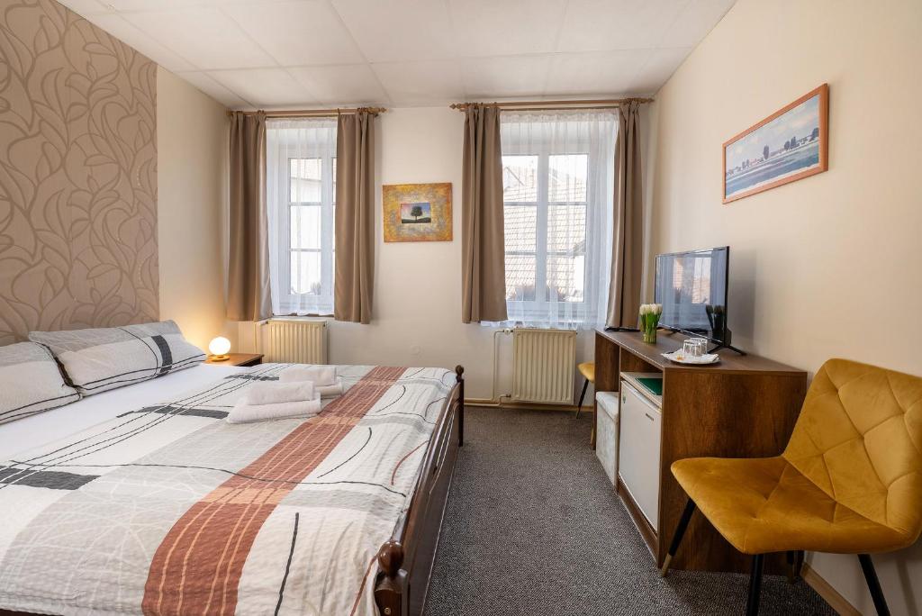 a bedroom with a bed and a desk and a television at Rodinný hotel Myslivna in Třeboň