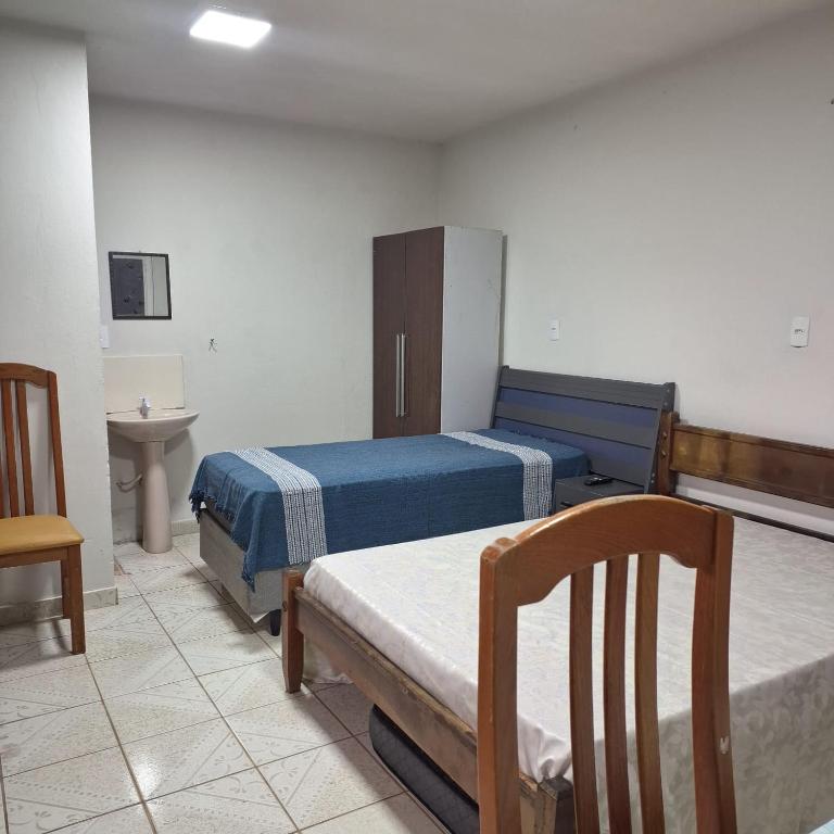 a room with two beds and a table and a sink at kitnet, com tv,wifi in Sorocaba