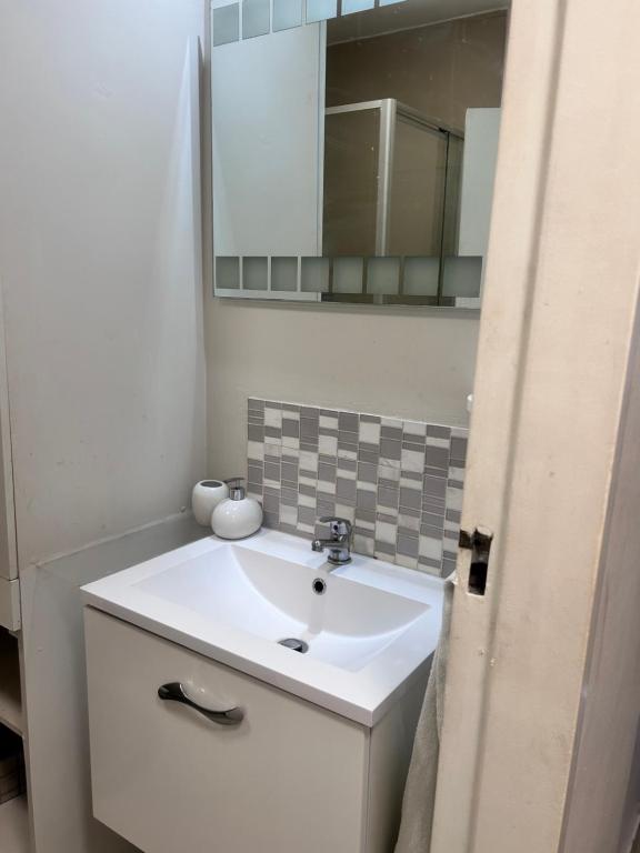 een badkamer met een witte wastafel en een spiegel bij 47 on Hyde Park in Kaapstad