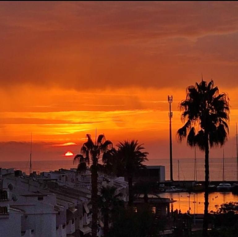 a sunset over a city with palm trees and buildings at Puebla de Farnals playa- Oasis Apartments - Costa de Valencia Beachside Stay in Puebla de Farnals