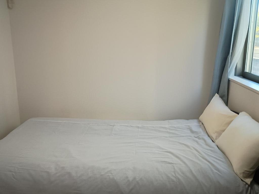 a bed with white sheets and pillows in a room at N's room & park ,Tokyo, Guest House - Vacation STAY 18814 in Tokyo