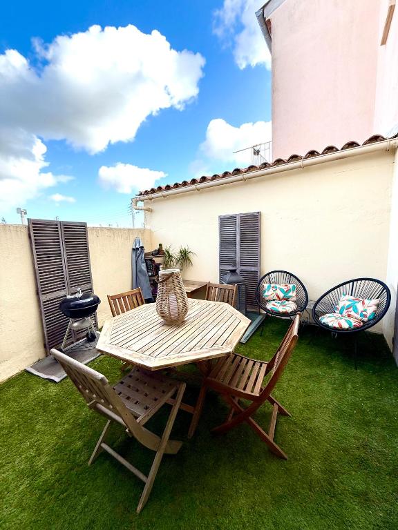 un patio avec une table et des chaises sur l'herbe dans l'établissement Appartement Narbonne centre, à Narbonne