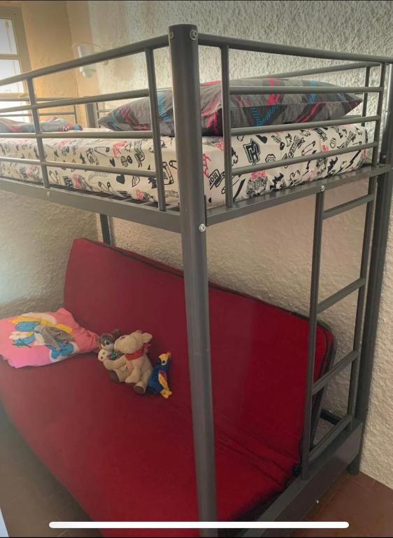 Ce lit superposé se trouve dans un dortoir doté d'un canapé rouge. dans l'établissement Location bord de mer, à Argelès-sur-Mer