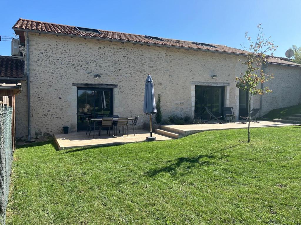 a house with a table and an umbrella and a lawn at La Grange 6 personnes in Boulazac