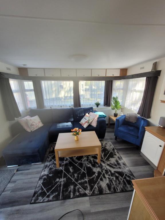 Una sala de estar con un sofá azul y una mesa. en The Sunny Bunny Holiday Home, en Ballantrae