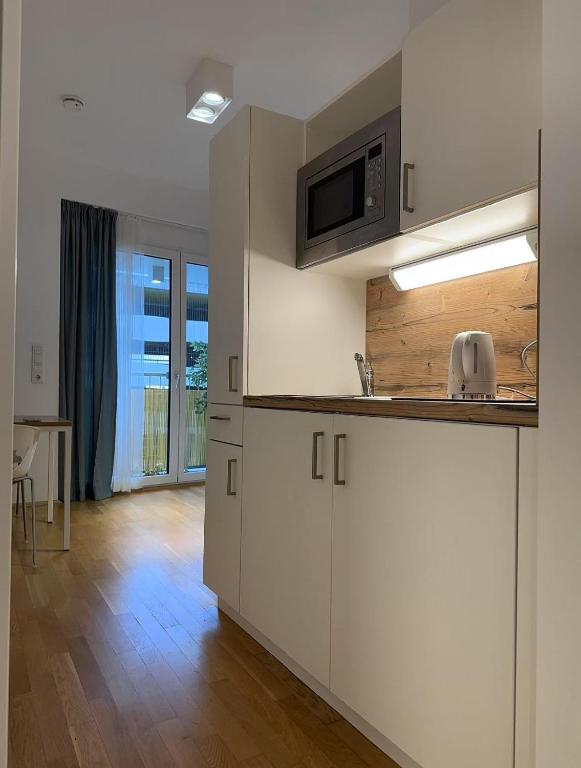 a kitchen with white cabinets and a microwave at München Messe Apartment in Munich