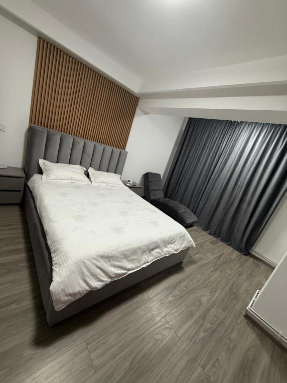 a bedroom with a large bed and a chair at Garsoniera de lux cu balcon in Craiova